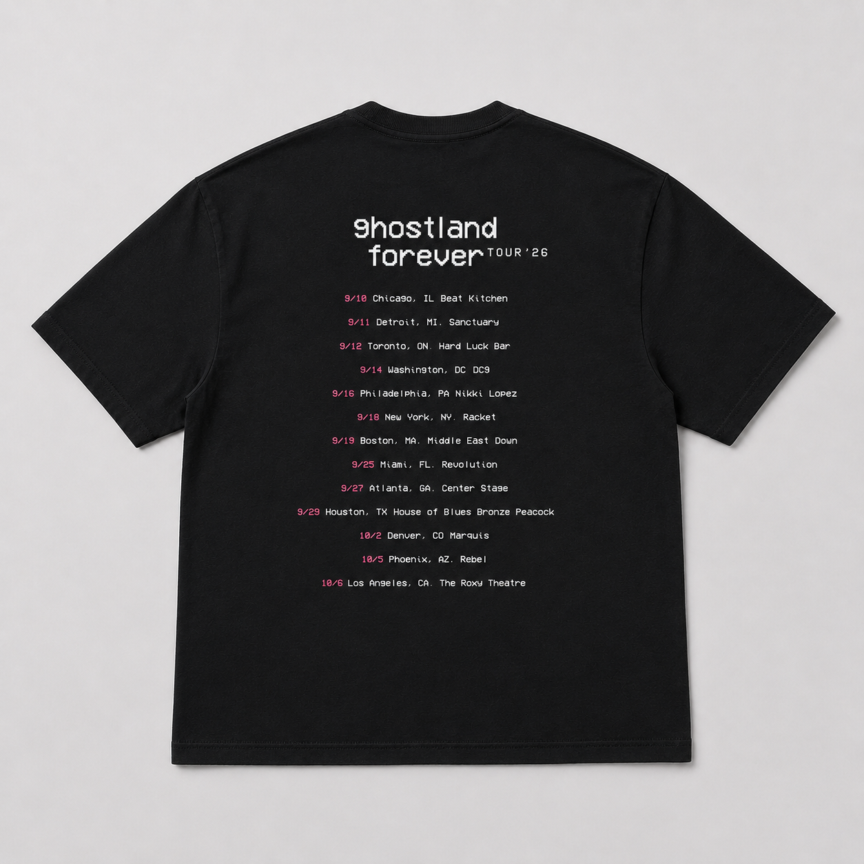 A black short-sleeve t-shirt laid flat against a light gray background, featuring a white and pink printed concert tour schedule for Ghostland Forever Tour '26 on the front.